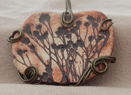 The focal is made of clay, and with the impressions of weeds in it and accented with iron oxcide.